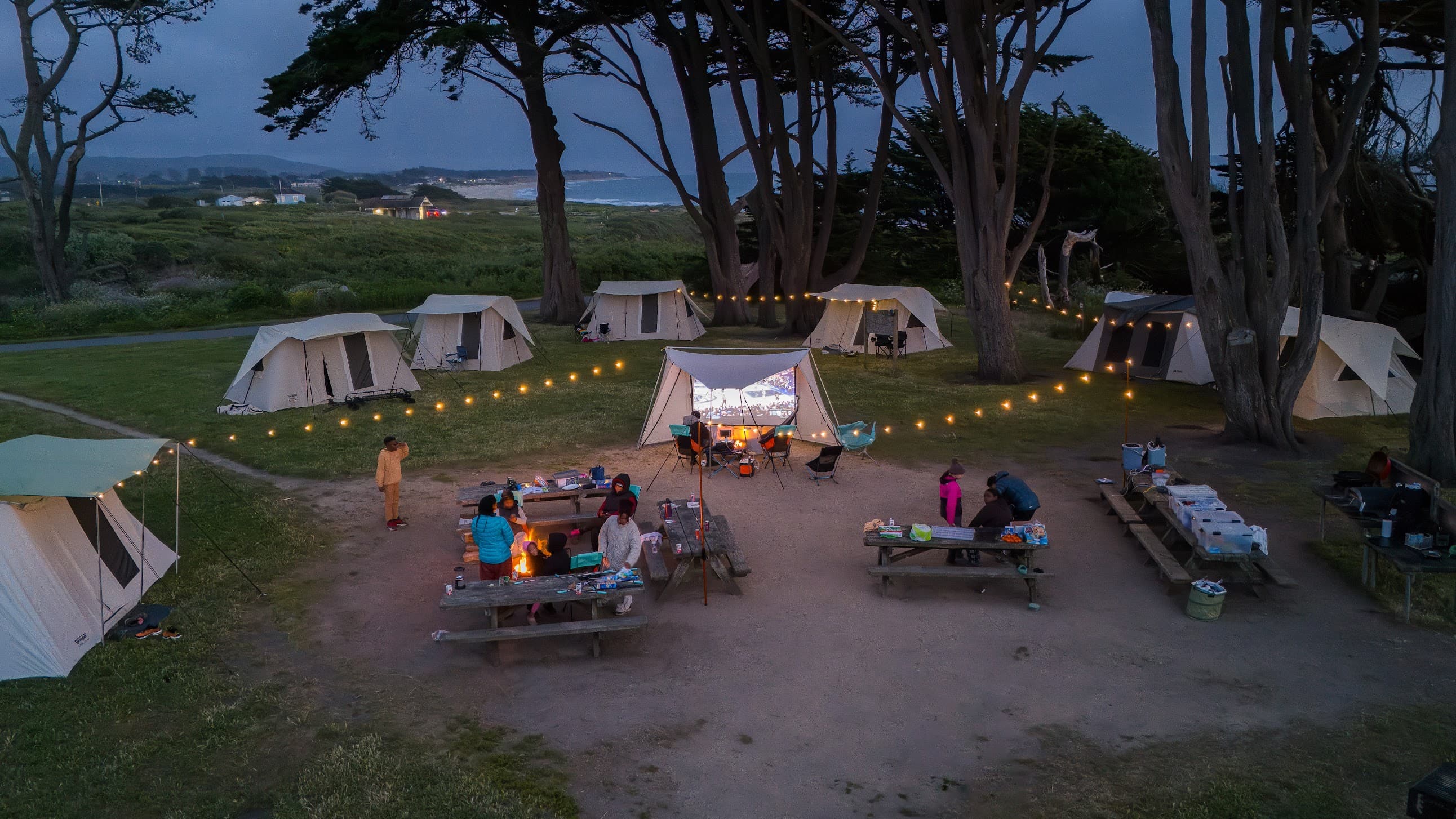 Evening camp with string lights and tents by the coast