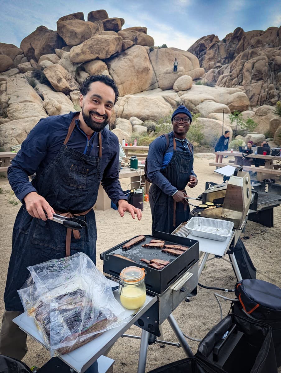 Community members grilling breakfast together at camp